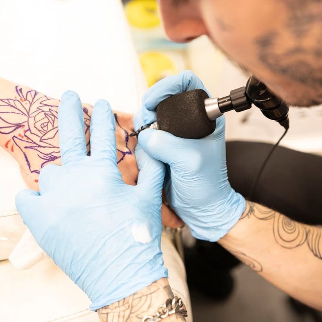 Tattoo artist tattoing hand